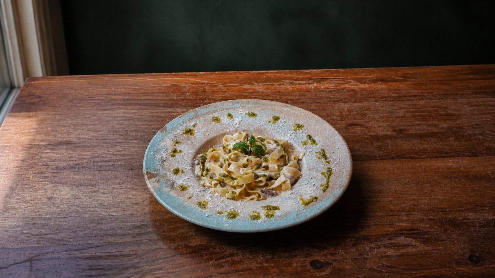 Fettuccini Alfredo, pesto damlalı mavi tabakta